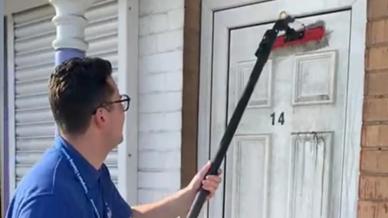 Tom cleaning a customer's door and glass with his water-fed brush